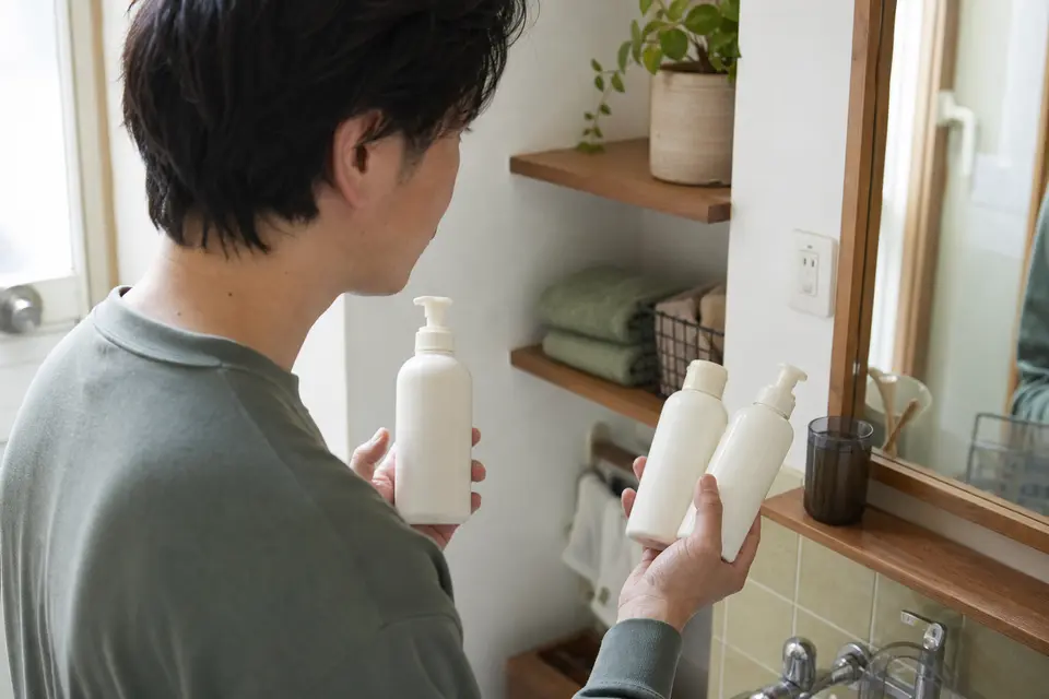 1本のポンプ容器と2本の容器を手に取り使い方を見比べる男性